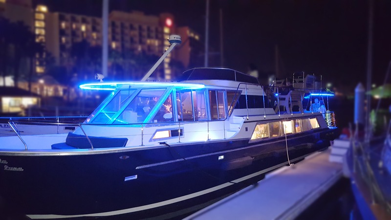 Luxury yacht with blue lights docked at night