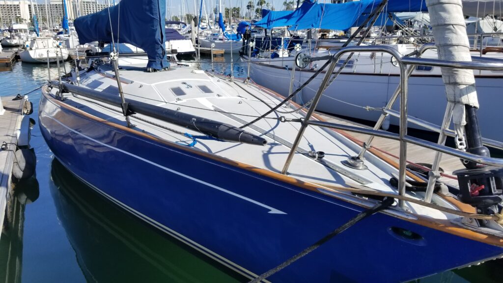 Blue sailboat docked at marina with other boats