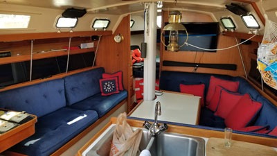 Cozy sailboat cabin with blue seating and kitchen sink