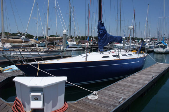 Blue sailboat docked at marina on sunny day
