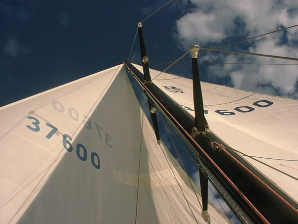 View up sailboat mast against blue sky