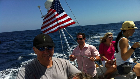 People sailing with American flag on sunny ocean
