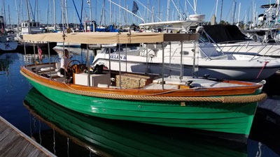 Green wooden boat docked at marina