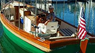 Person steering green wooden boat with American flag
