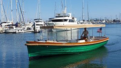 Green boat cruising in marina with sailboats