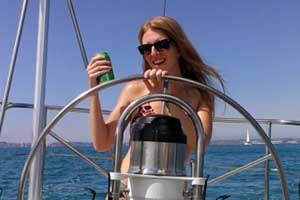 sarah Woman steering a sailboat holding a drink