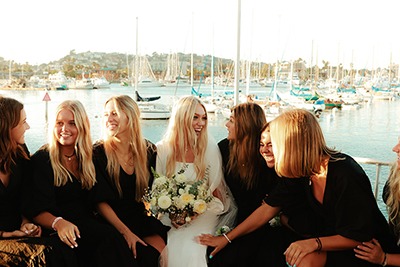 Bride with bridesmaids by marina at sunset
