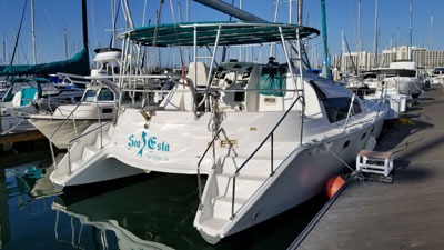 White catamaran docked at marina under blue sky