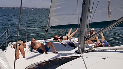 People relaxing on a sailboat under sunny skies