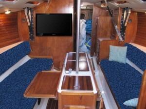 Wood-paneled sailboat cabin with blue seating and TV