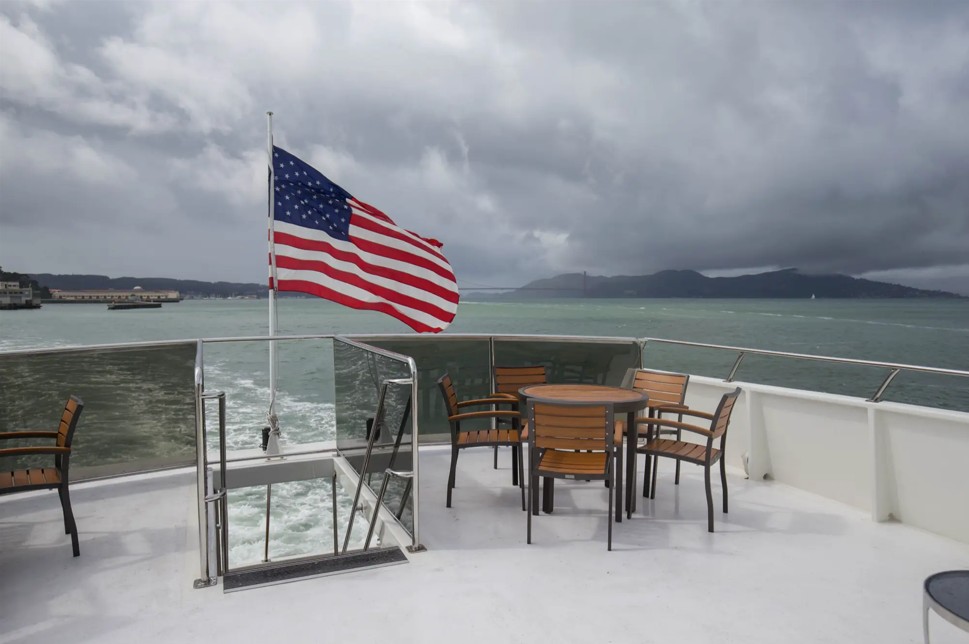 100_luxury_yacht_pacifica5 US flag on boat deck, ocean and hills.